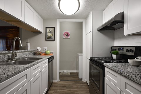a kitchen with white cabinets and granite counter tops and a black stove