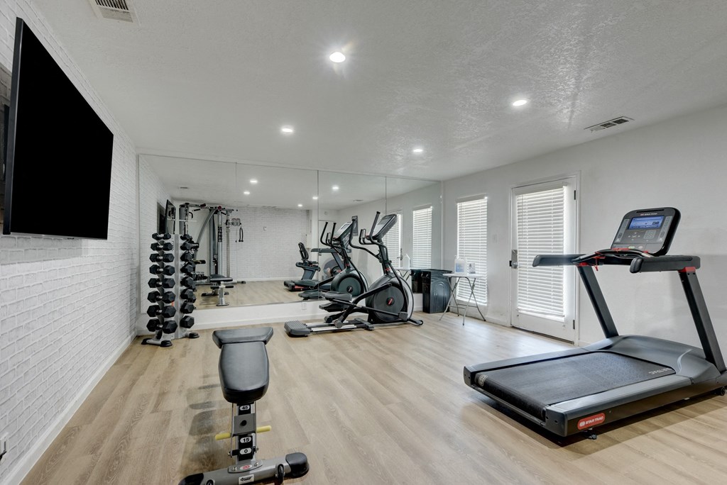 a gym with exercise equipment and a tv on the wall