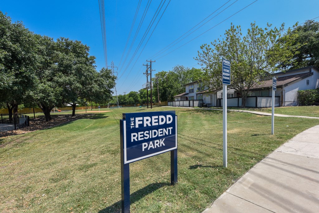 a sign for freed residential park in the grass near a sidewalk