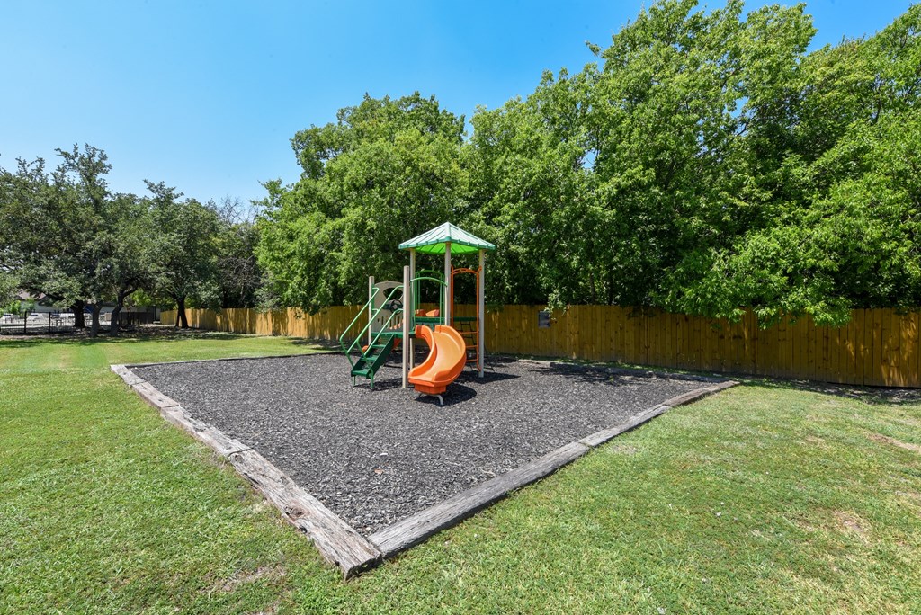 a playground with a swing set in a yard with trees
