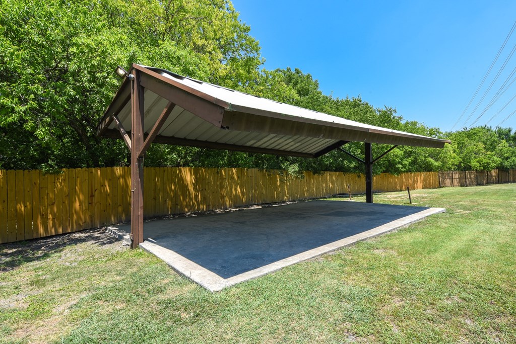 a covered area with a basketball court in a backyard