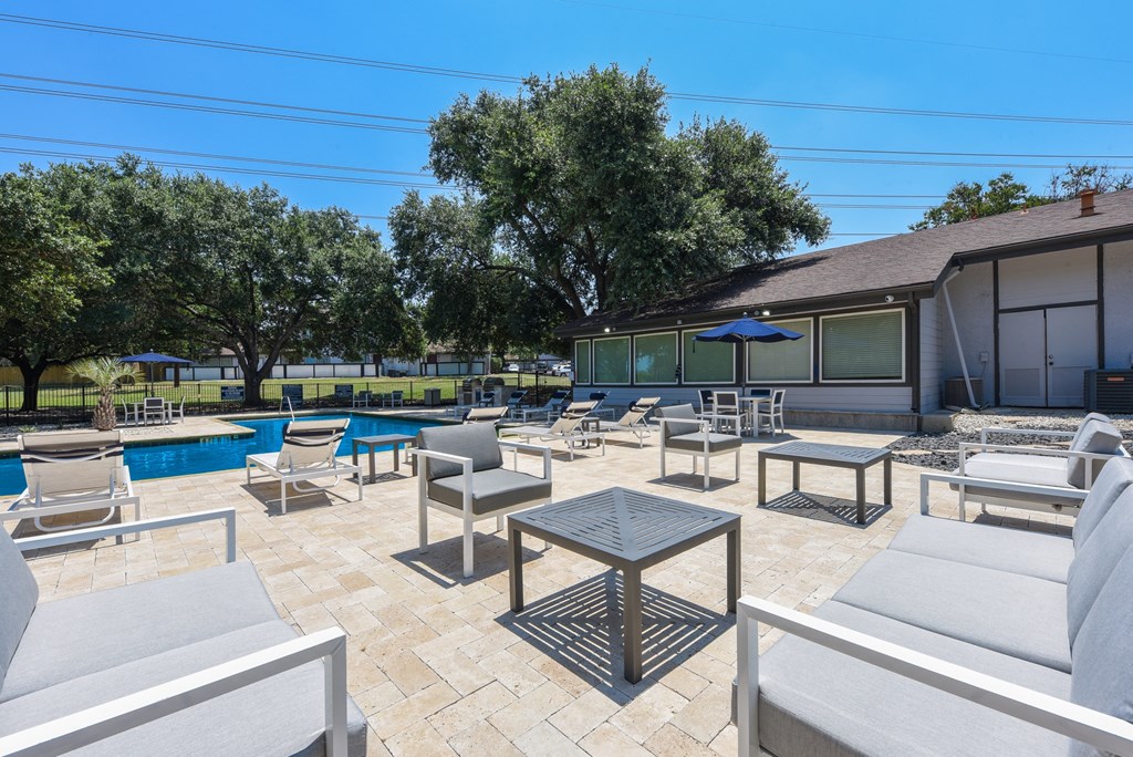 a patio with chairs and tables next to a pool