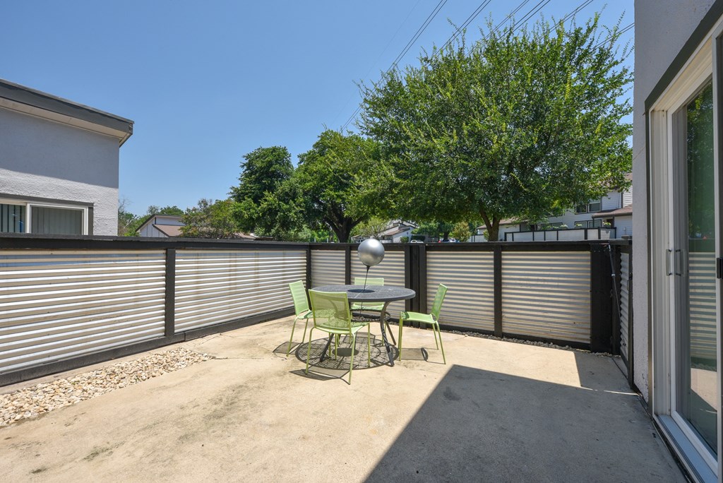 a patio with a table and chairs and a privacy fence