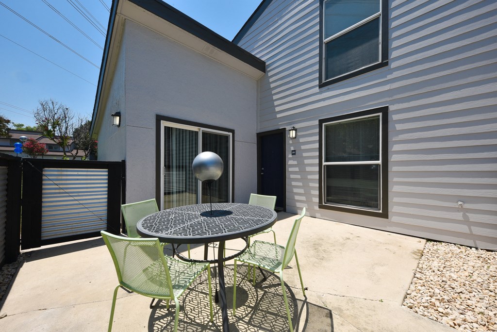 a patio with a table and chairs in front of a house