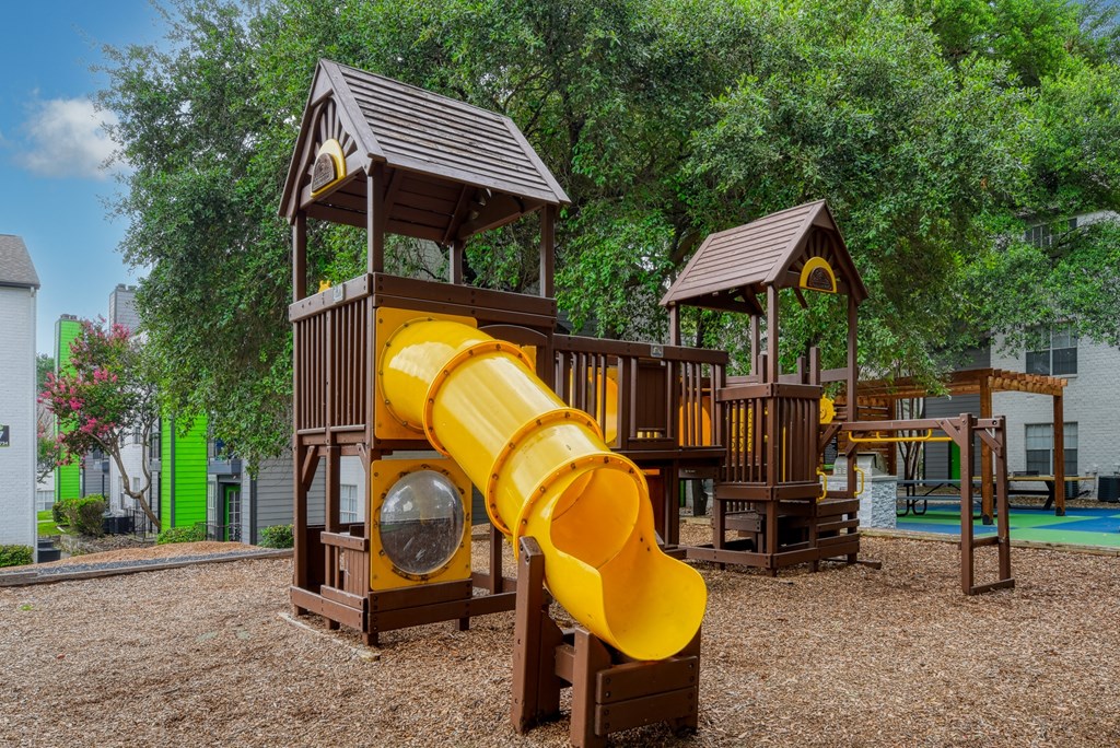 a yellow slide on a playground in a park