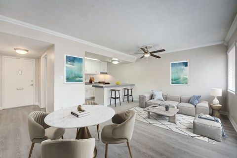 A living room with a white table and grey chairs.