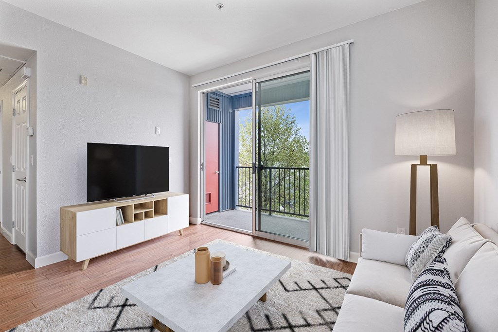 a living room with a couch and a tv and a balcony