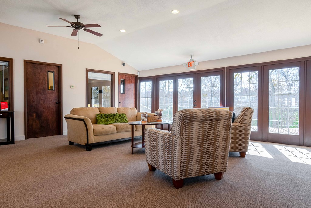 a living room with a couch and chairs and a ceiling fan