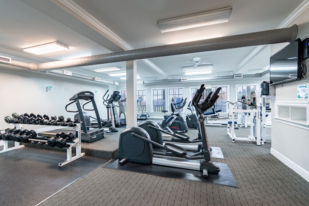 a gym with cardio equipment and weights at the district at highland village apartments