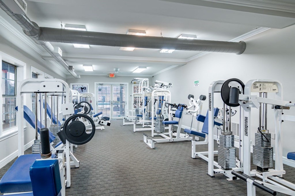 a spacious fitness room with cardio equipment and weights
