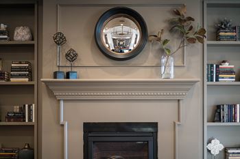 A decorative fireplace with built-in shelves and a circular mirror above the mantle.