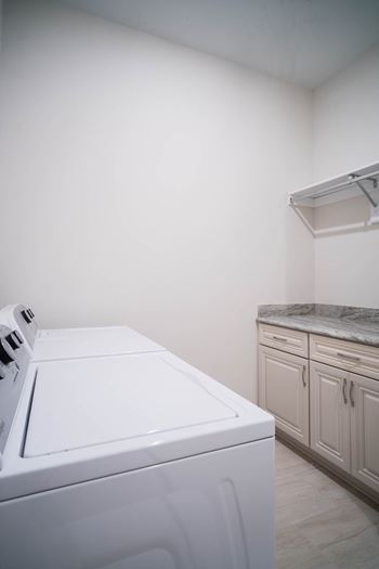 A bright laundry room with a washer, dryer, and built-in storage.