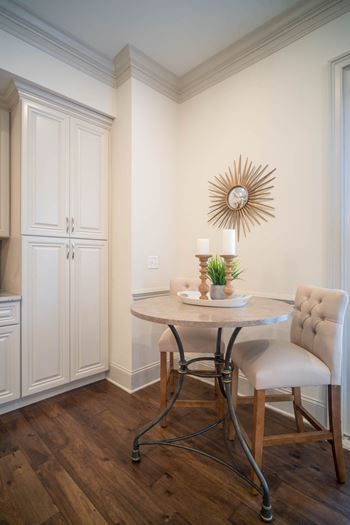 A small dining corner with a round table, tufted chairs, and wall art.