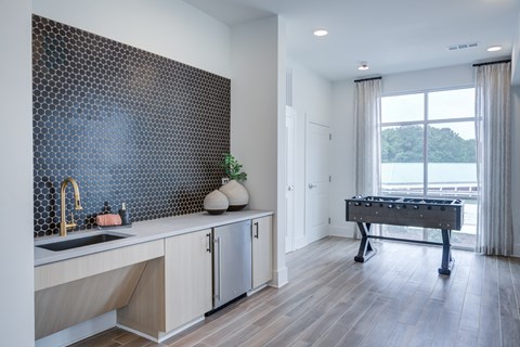 A kitchen with a sink, a fridge, and a pool table.