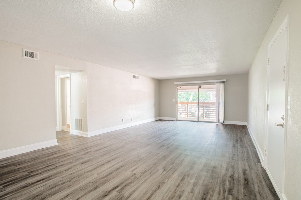 an empty living room with wood flooring and a window