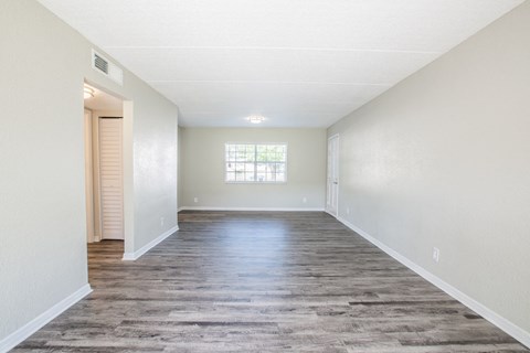 an empty living room with a hard wood floor and a window