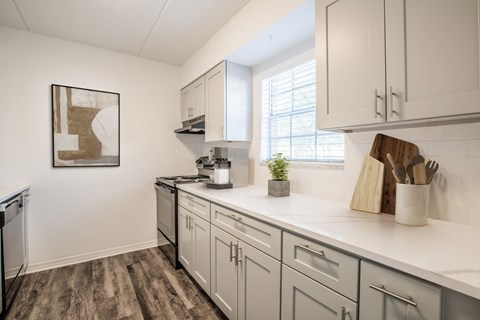 a white kitchen with white cabinets and a window