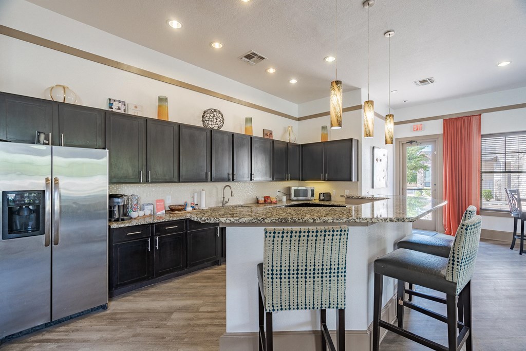 a kitchen with black cabinets and a bar with two stools