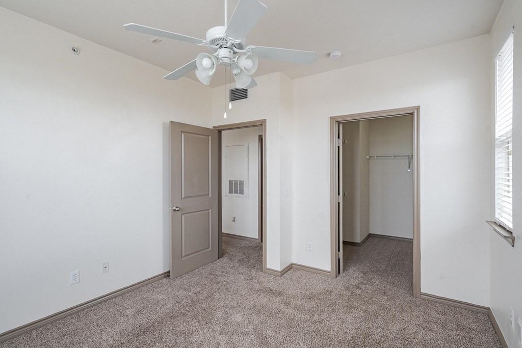 a bedroom with white walls and a ceiling fan