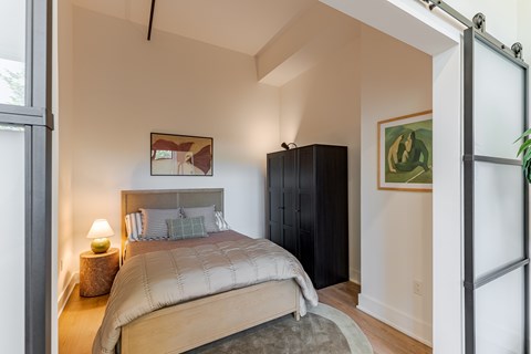 A bedroom with a bed, nightstand, and a cabinet.