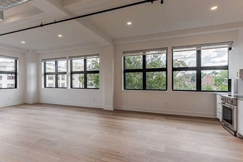 A large empty room with wooden floors and windows.