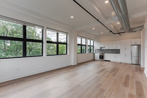 A spacious room with wooden floors and large windows.