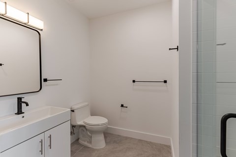 A bathroom with a toilet, sink, and a mirror.