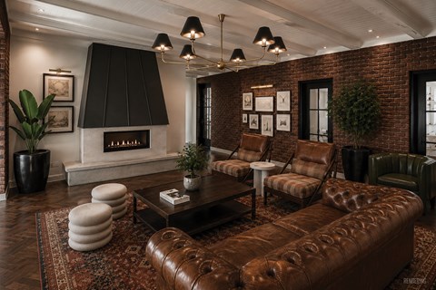 A living room with a brown leather couch and a fireplace.
