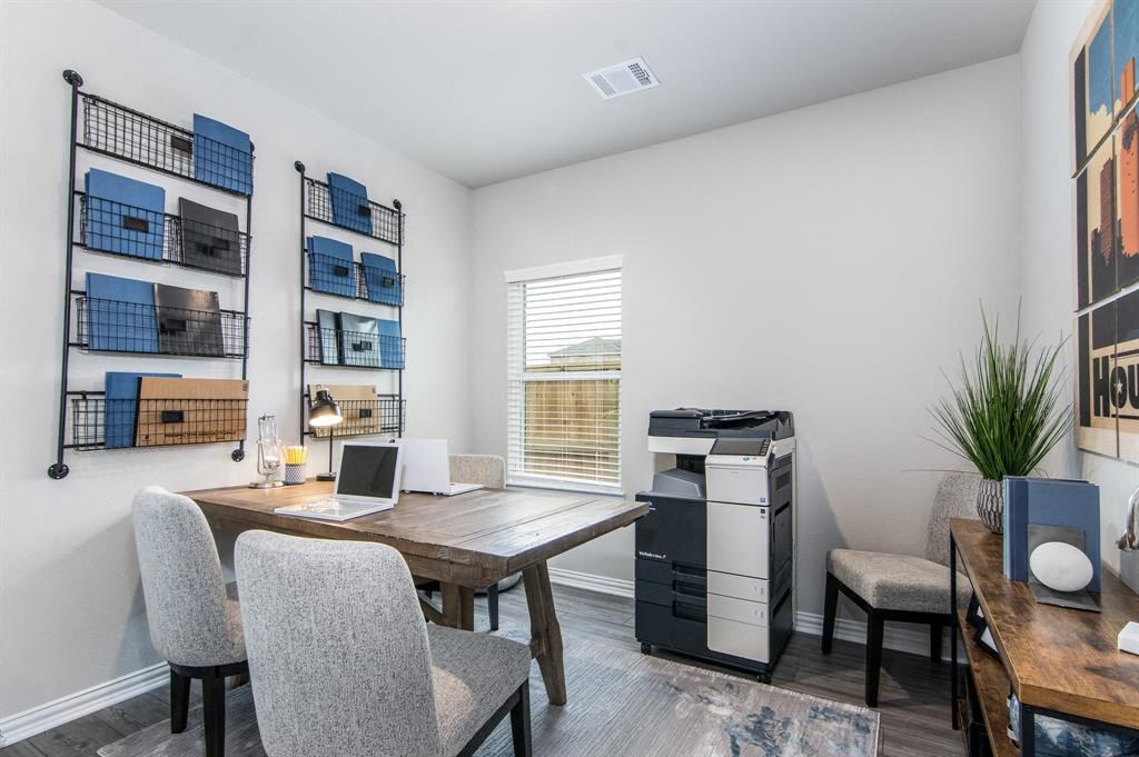 a room with a table and chairs and a desk with a laptop and a printer
