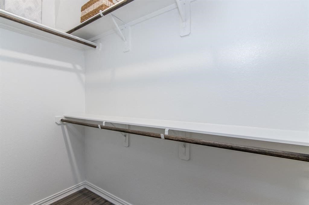 a walk in closet with white walls and a white shelf