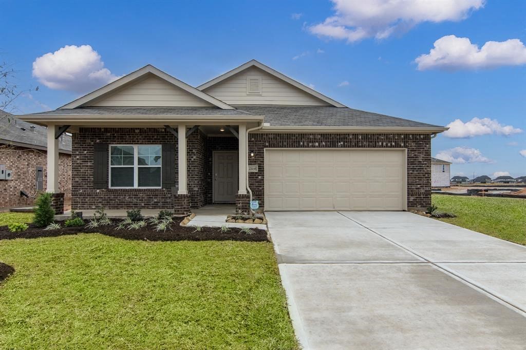 2-BR Homes for Rent in Katy, TX - Villas at Sunterra - Front Yard of a Brick House with a Garage, a Driveway, and Well-Maintained Green Grass