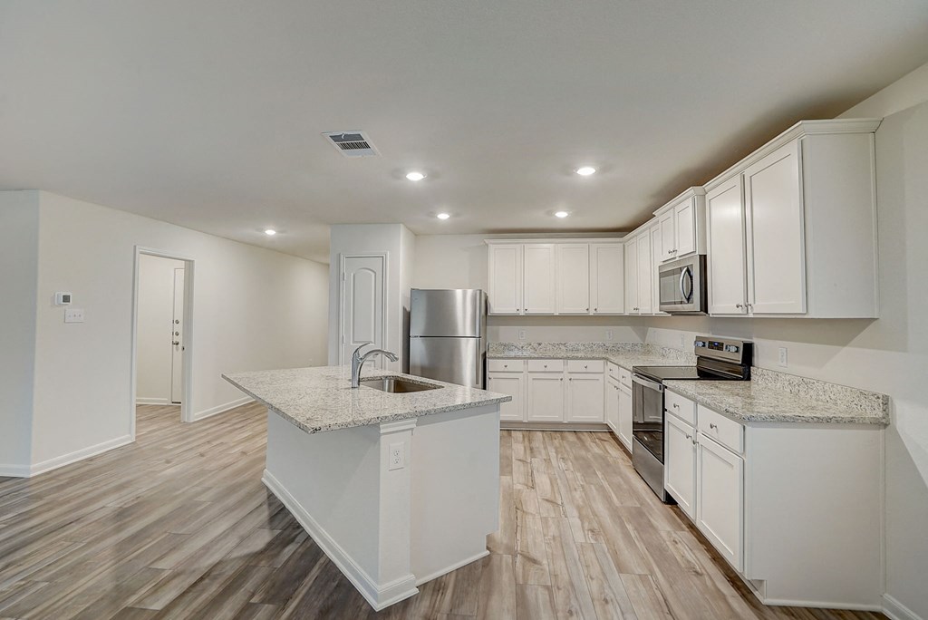 an open kitchen with white cabinets and marble counter tops