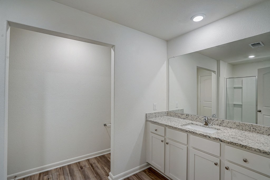 the spacious bathroom has a large mirror and white cabinets