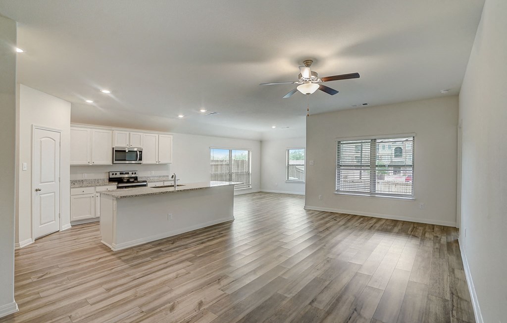 an empty kitchen and living room with a ceiling fan