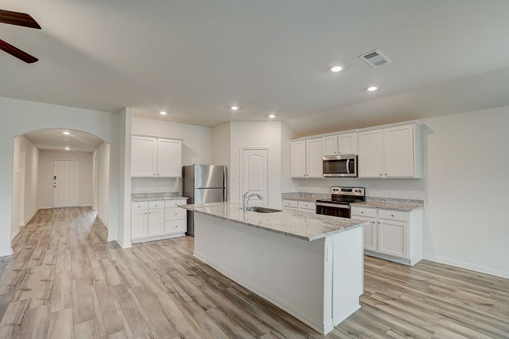 a kitchen with white cabinets and a marble counter top