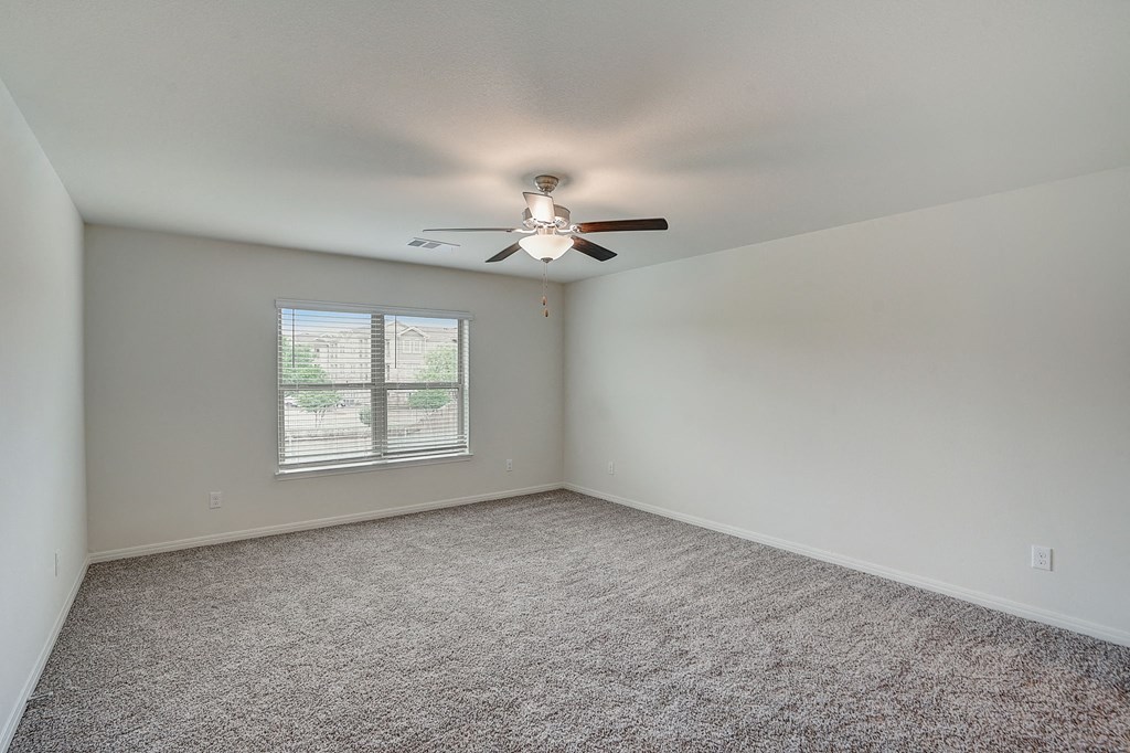 an empty room with a ceiling fan and a window