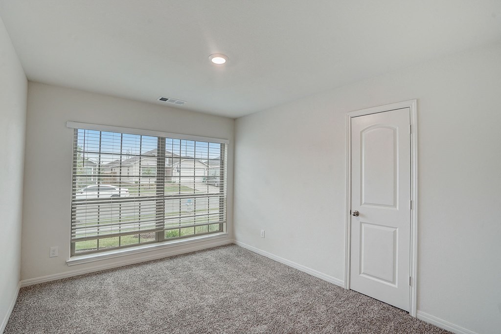 an empty bedroom with a large window and a white door
