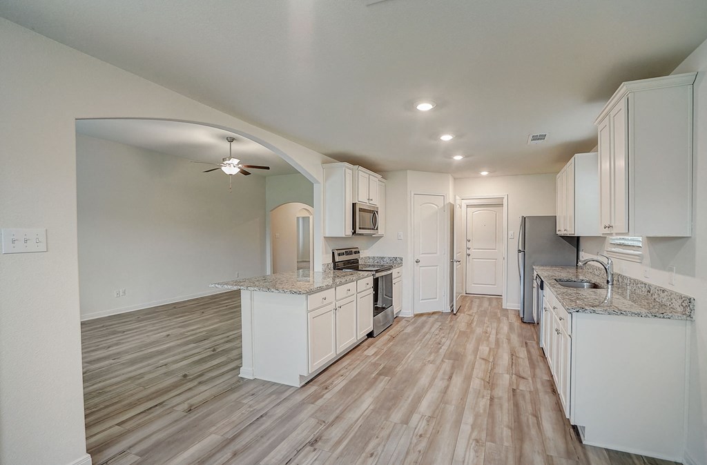 an open kitchen with white cabinets and marble counter tops