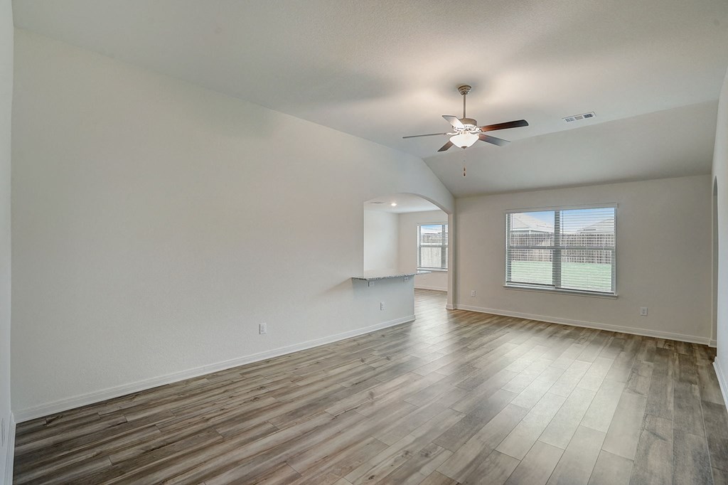 an empty living room with hardwood floors and a ceiling fan