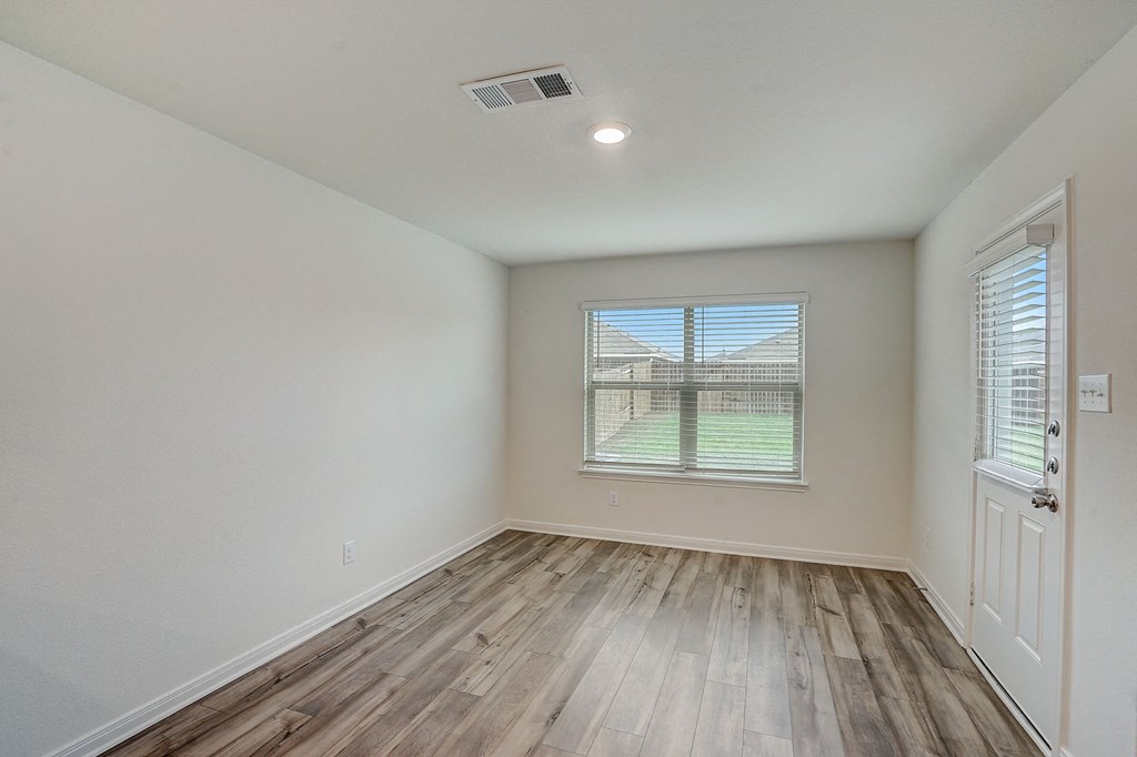 an empty living room with wood floors and a window