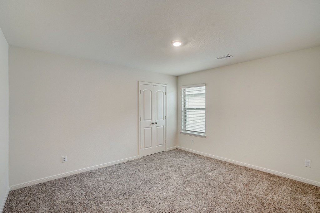 an empty living room with carpet and a white door