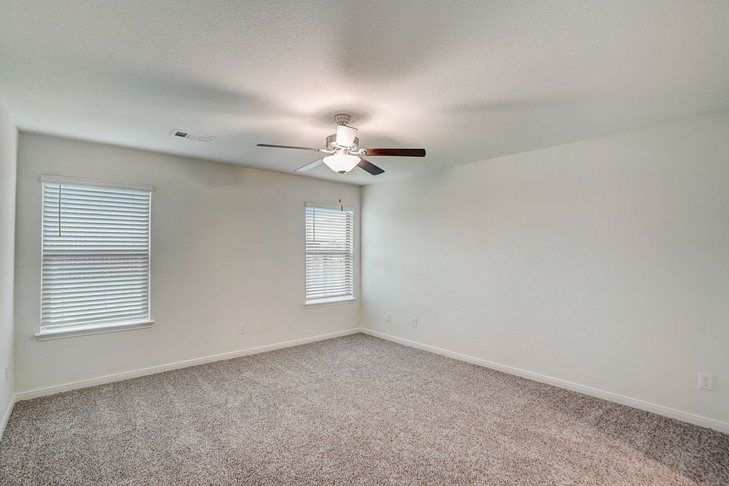 an empty living room with a ceiling fan and a window