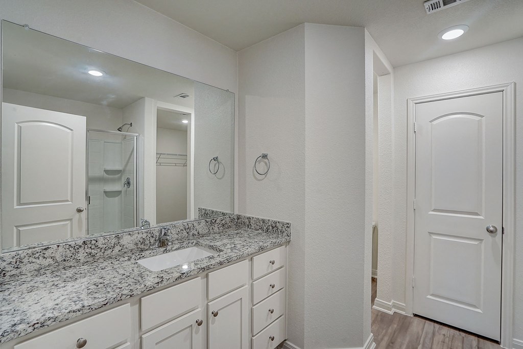 a bathroom with white cabinets and a sink and a mirror