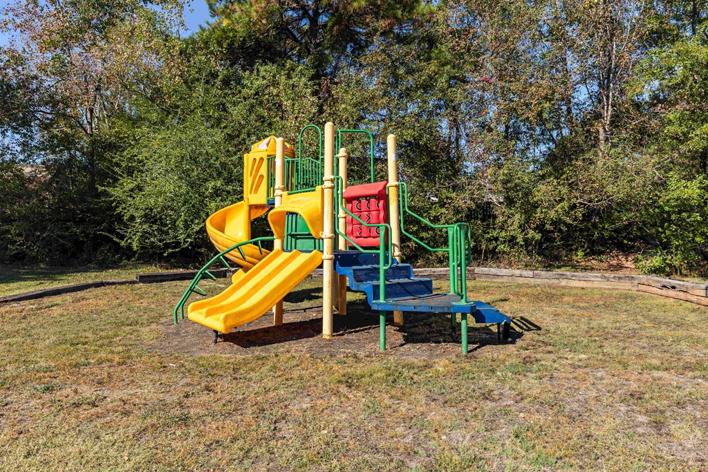 Twin Oaks Apartments in Hattiesburg Mississippi photo of a playground with a yellow and green slide and a blue and red slide
