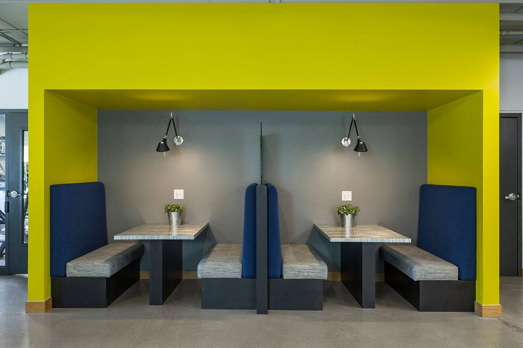 a dining room with yellow and gray walls and tables with blue chairs