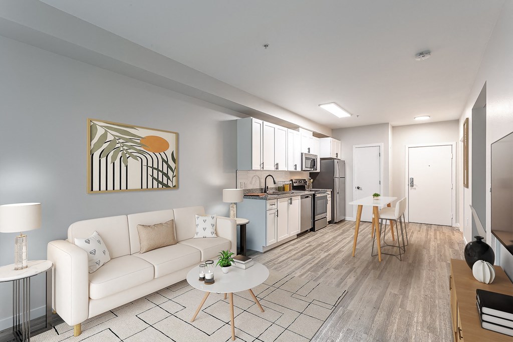 a living room with a couch a table and a chair and a kitchen with a stove and