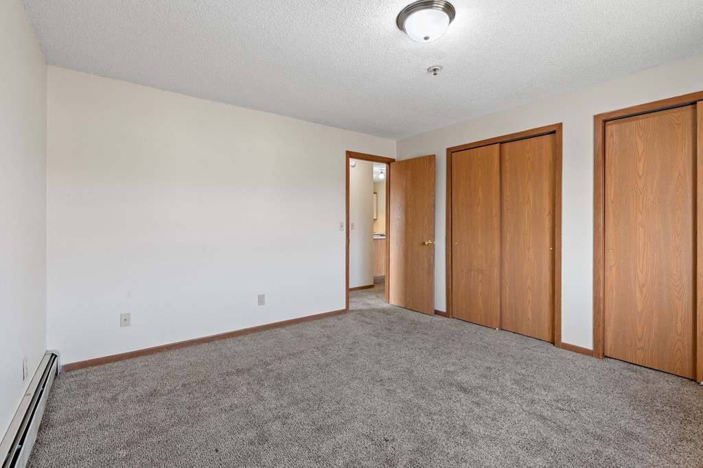 an empty living room with carpet and wood doors