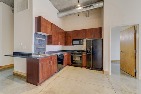 A kitchen with a black counter top and brown cabinets.