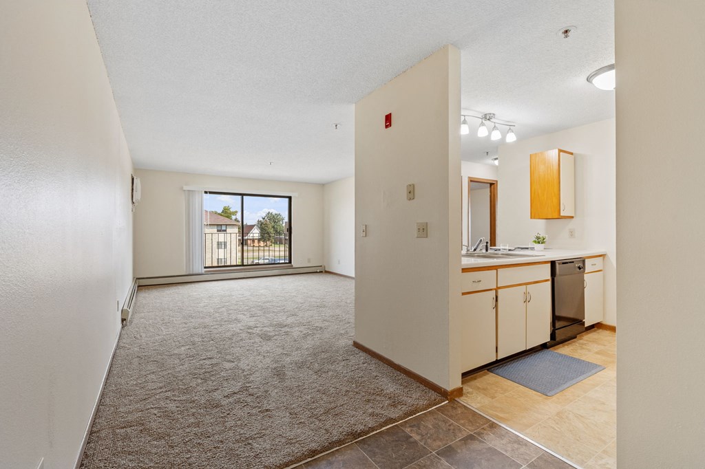an empty living room and kitchen with a door to a balcony