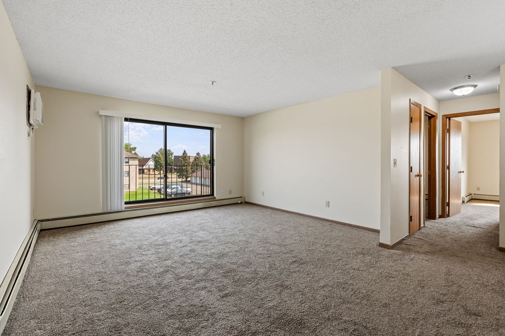 an empty living room with a large window and carpet